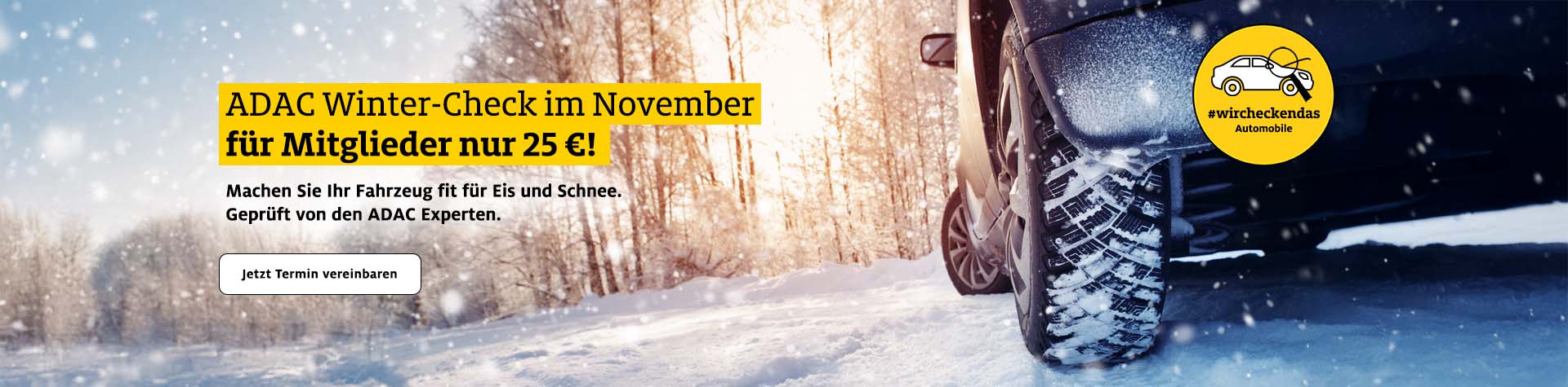 Ein schwarzes Auto fährt bei Sonnenlicht auf einer verschneiten Straße im Wald.