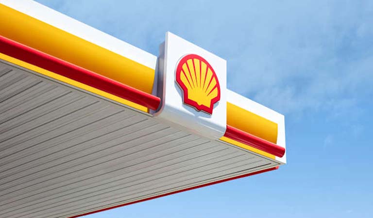 Tankstellendach mit Shell Logo in Gelb und Rot vor klarem blauen Himmel