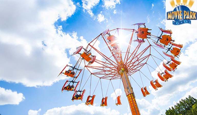 Eine bunte Karussellattraktion mit fröhlichen Menschen vor blauem Himmel