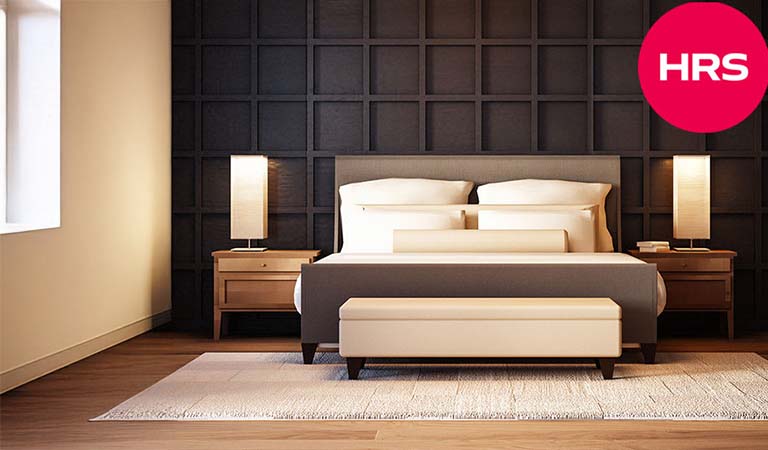 Modern Schlafzimmer mit dunkler Wand, Holzboden, heller Bettwäsche und zwei Lampen