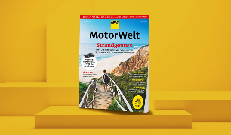 Eine Frau mit Rucksack geht einen hölzernen Steg Richtung Strand bei sonnigem Wetter