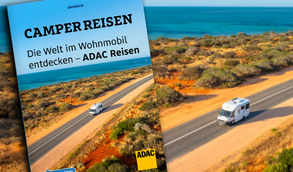 Ein weißes Wohnmobil fährt fröhlich auf einer Küstenstraße mit blauem Meer entlang