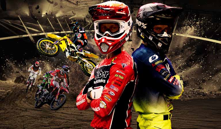 Zwei Motocross-Fahrer in bunter Kleidung stehen Rücken an Rücken und schauen ernst