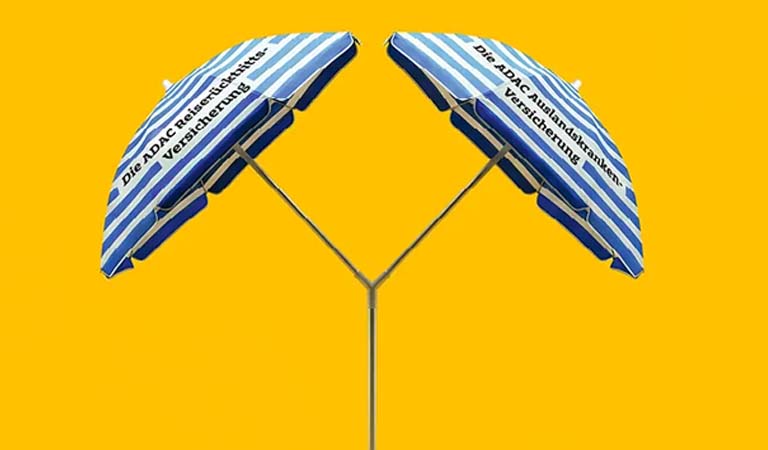 Zwei blaue gestreifte Sonnenschirme mit deutscher Schrift auf gelbem Hintergrund
