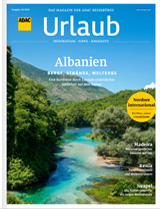 Ein türkisblauer Fluss fließt durch eine grüne Landschaft unter blauem Himmel