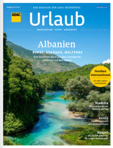 Ein türkisblauer Fluss schlängelt sich durch grüne Berge unter blauem Himmel