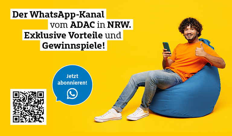 Ein Mann mit lockigem Haar lächelt freundlich, sitzt auf einem blauen Sitzsack und hält ein Handy